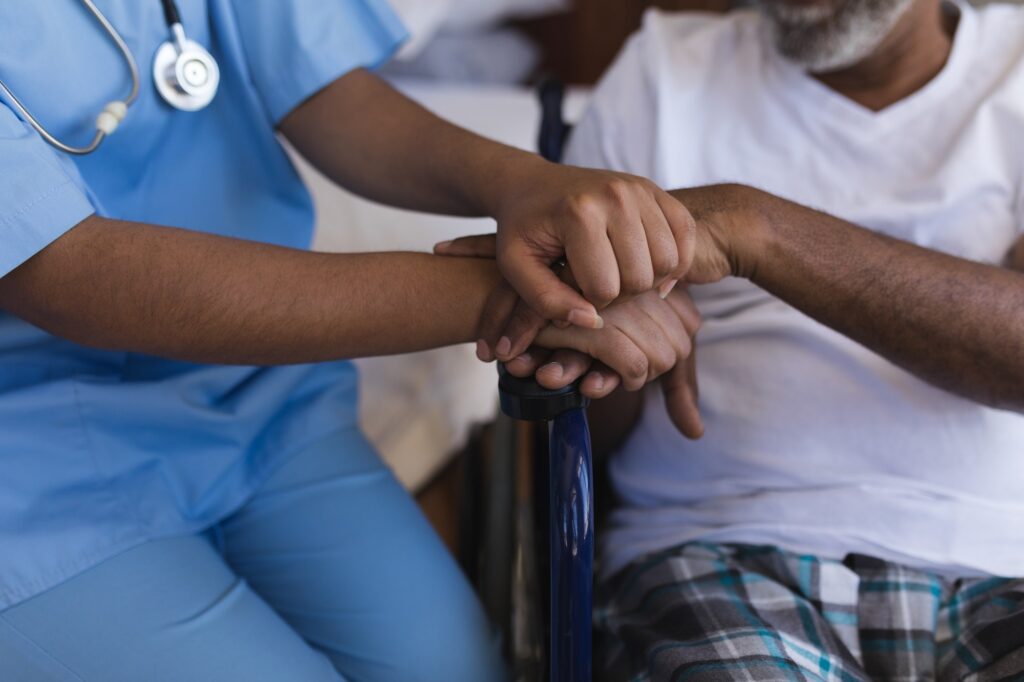 Mid section of young African American female doctor consoling senior African American man at home